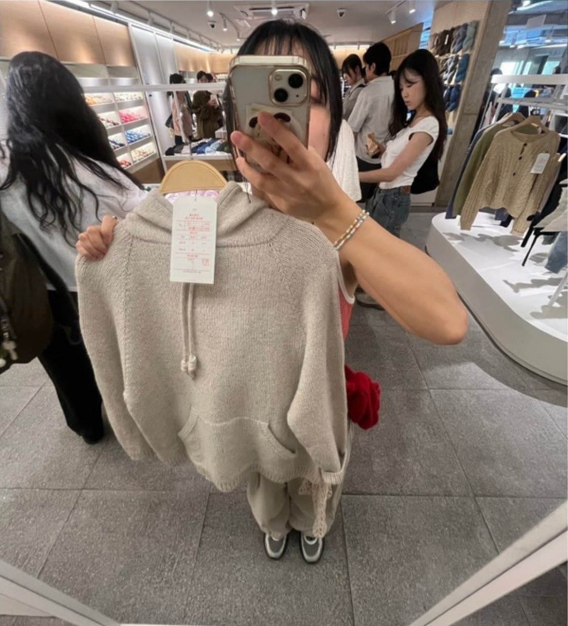 Dabin holding up a knitted hoodie in a shop